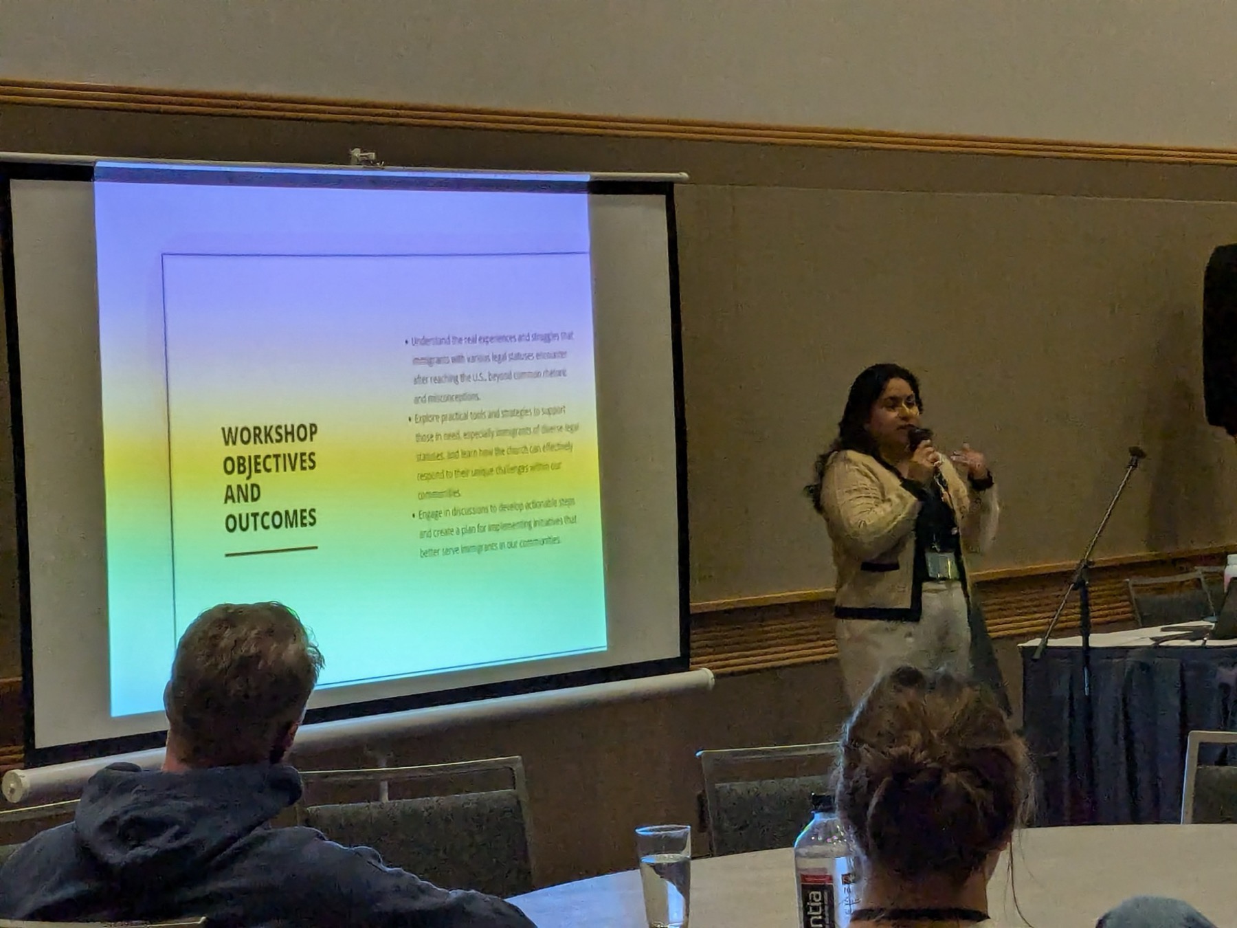 Rosa J. Bello speaking with a microphone at a conference workshop